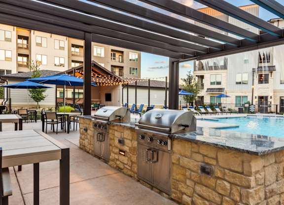 A barbecue grill is situated next to a pool.