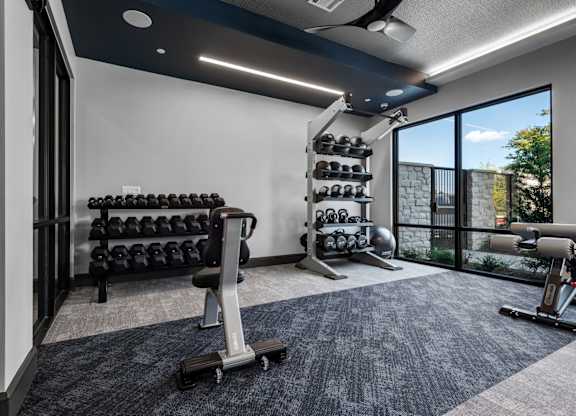 A spacious home gym with a variety of equipment including dumbbells, weight plates, and a bench.