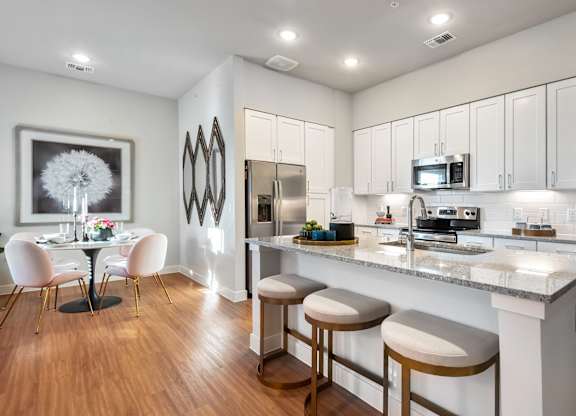 A kitchen with white cabinets and a bar area with stools.