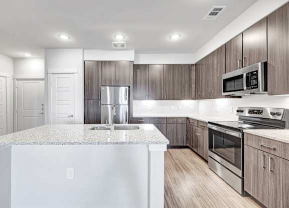 A modern kitchen with a granite countertop and stainless steel appliances.