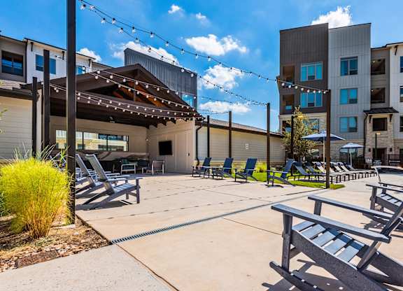 A sunny day at the poolside with lounge chairs and a building in the background.