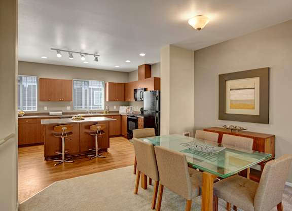 A modern kitchen with a glass dining table and chairs.