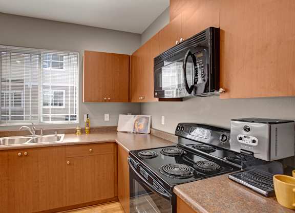 A kitchen with a black stove top oven and a black microwave above it.