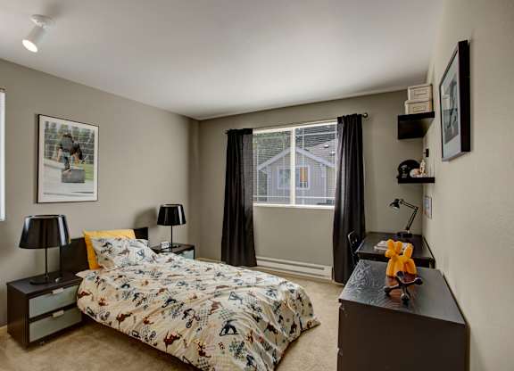 A bedroom with a bed, nightstand, and a window with curtains.