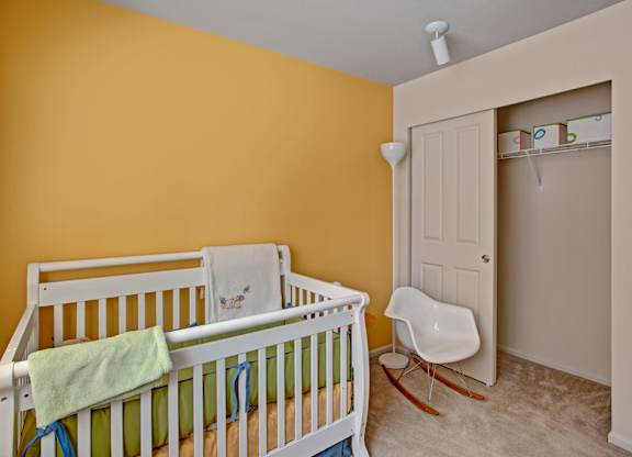 A baby's room with a white crib and a white rocking chair.