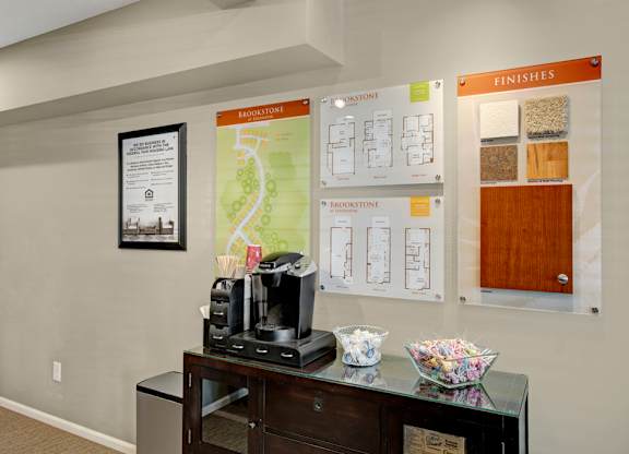 A coffee maker on a counter with a map and brochures on the wall.