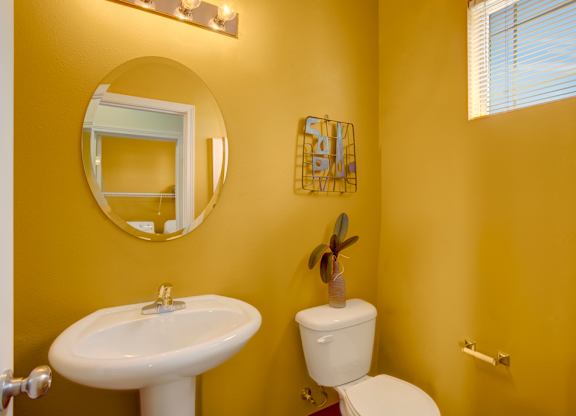 A bathroom with yellow walls has a white toilet and sink.