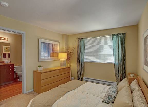 A bedroom with a large bed and a dresser with a mirror.