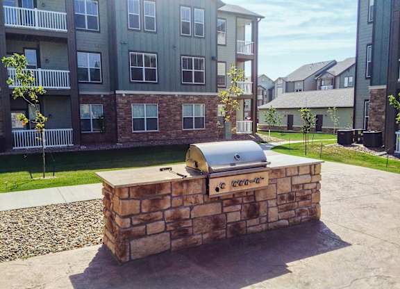 A brick BBQ grill in front of apartment buildings.