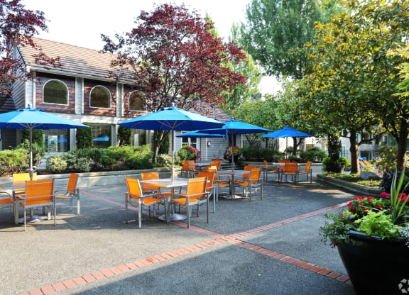 a patio with tables and umbrellas in front of a building