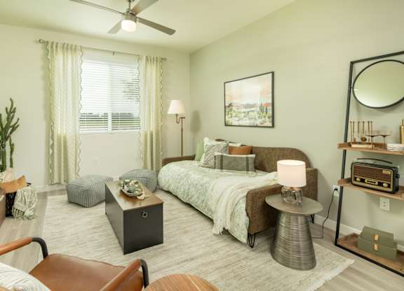 A bedroom with a bed, a chair, a table, and a ceiling fan.
