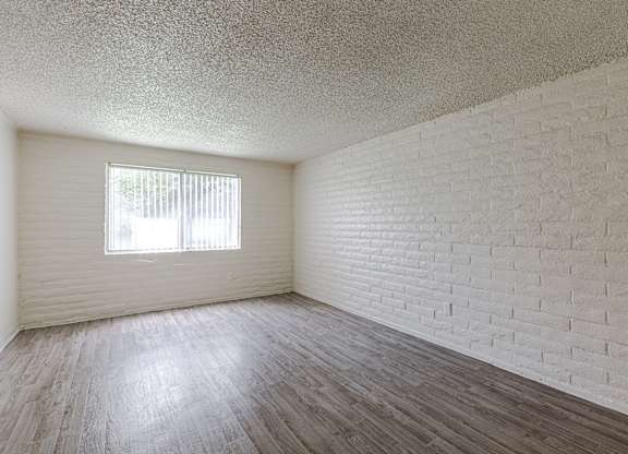 A room with a window and a brick wall.