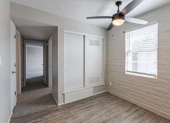 A room with a ceiling fan and a window with blinds.