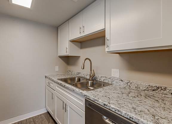 A kitchen with a marble countertop and white cabinets.