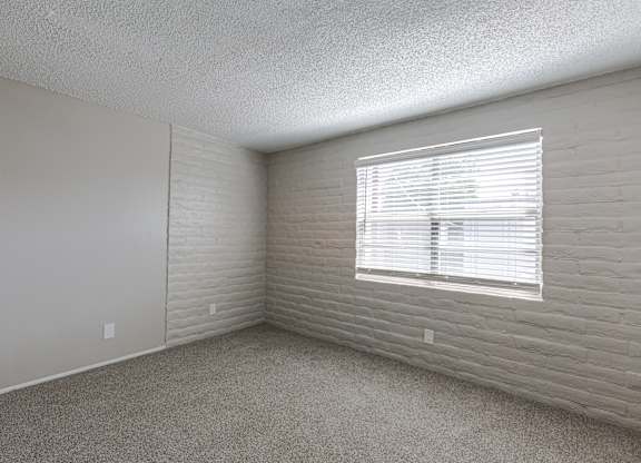 A room with a window covered by white blinds.