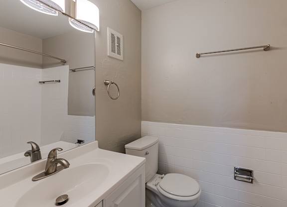 A white bathroom with a toilet, sink, and mirror.