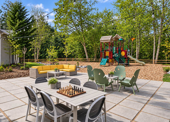 A backyard with a table, chairs, and a chess board.