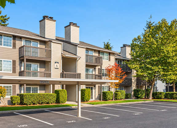 Apartment complex with a parking lot in front.