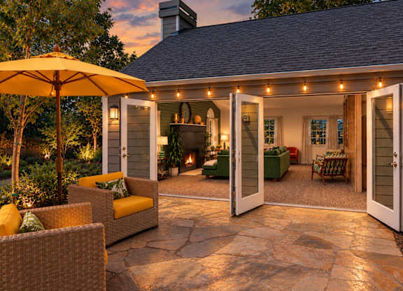 A patio with a yellow umbrella and chairs.