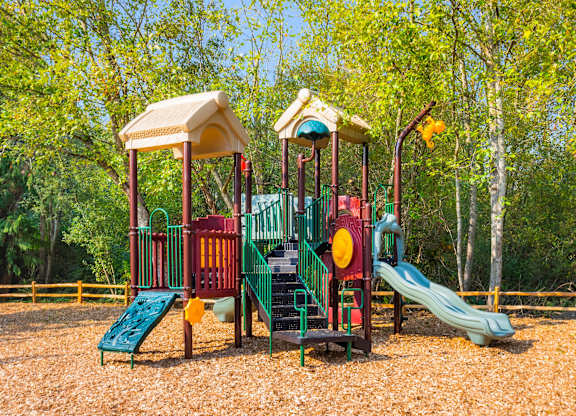 A playground with a green slide and a red and yellow structure.