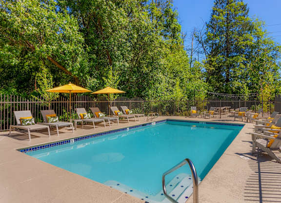 A swimming pool surrounded by yellow chairs and umbrellas.