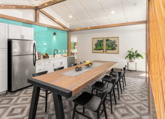 A kitchen with a wooden table and black chairs.