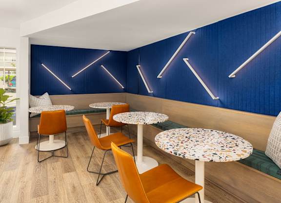 A blue wall with neon lights and a table with chairs in front of it.