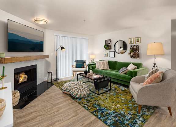 A living room with a fireplace, a green couch, and a painting on the wall.