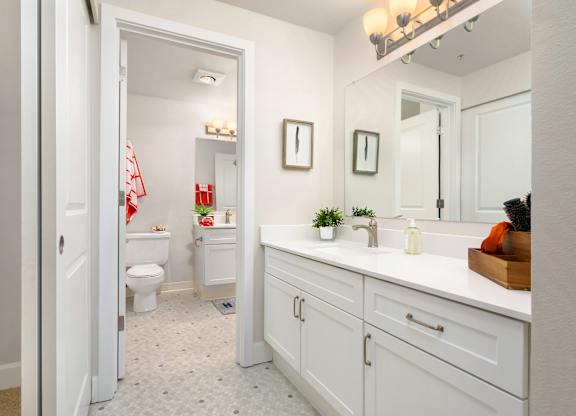 A white bathroom with a toilet, sink, and mirror.