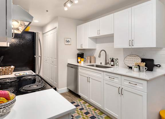 A kitchen with white cabinets and a black refrigerator.