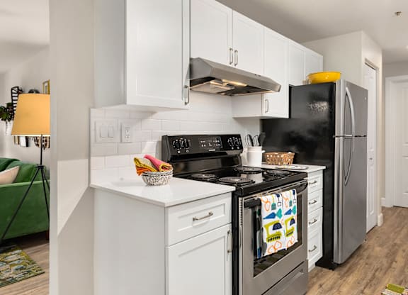 A modern kitchen with white cabinets and a black stove top oven.