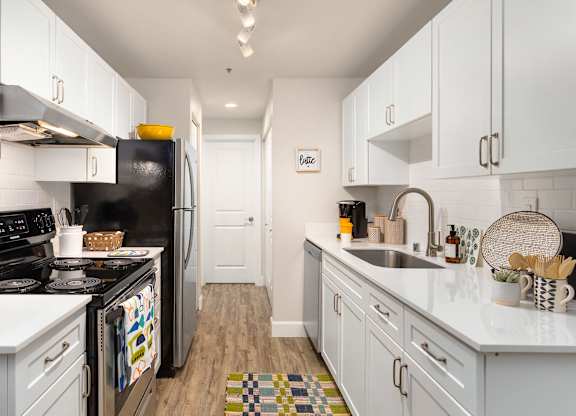 A kitchen with white cabinets and a black refrigerator.