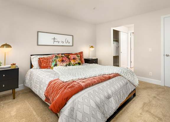 A bedroom with a bed, nightstands, and a framed picture on the wall.