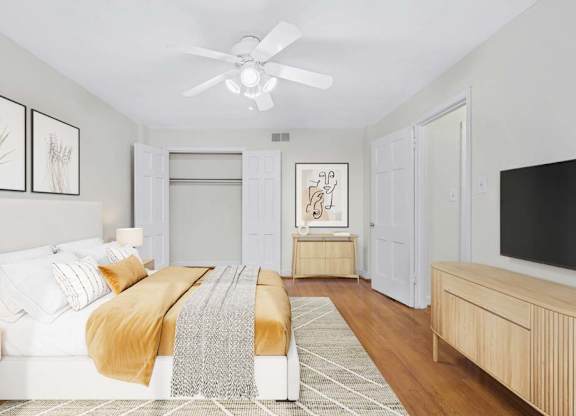 A bedroom with a bed, a bench, and a ceiling fan.