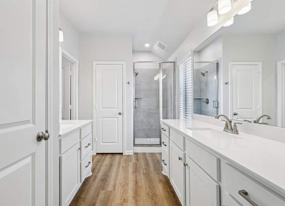 A white bathroom with a walk-in shower and a vanity.
