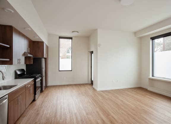 an empty living room and kitchen with wood flooring and a window
