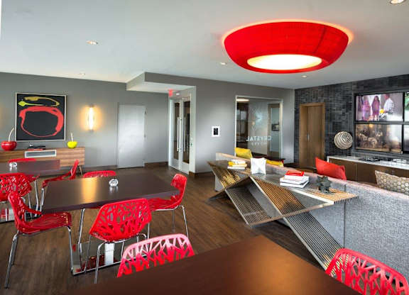 A modern living room with a grey couch and red chairs.