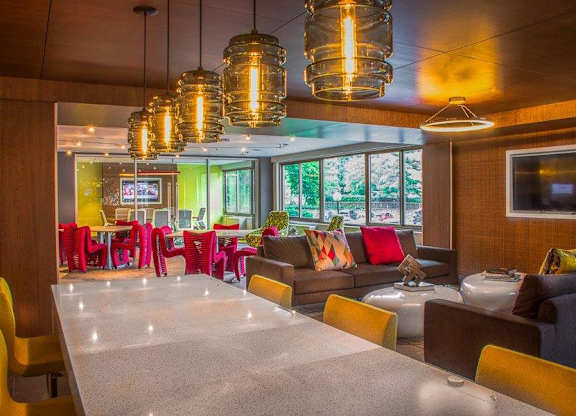 A modern dining area with a long table and colorful chairs.