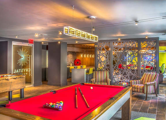 A pool table with a red cloth and a pool cue on it.