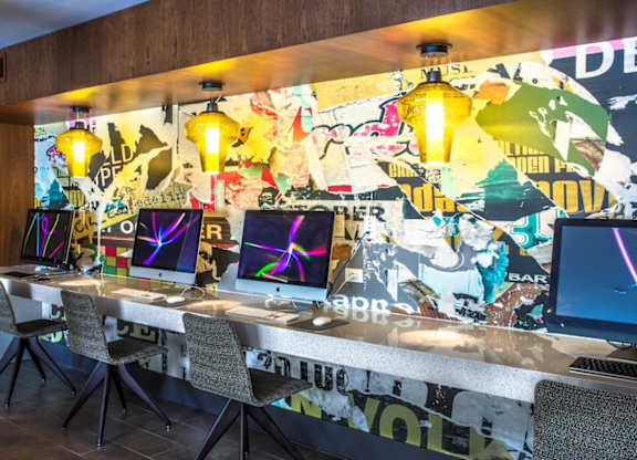 A room with a long table and chairs with a wall covered in posters.