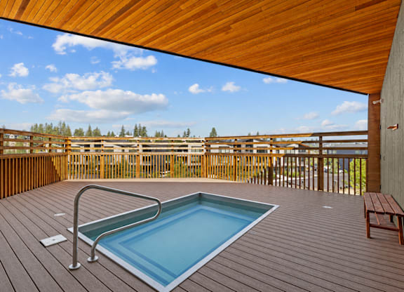A wooden deck with a pool and bench.