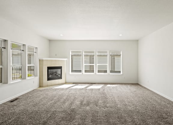 an empty living room with a fireplace and windows