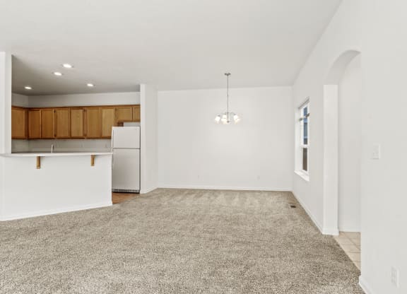 a spacious living room with a kitchen in the background