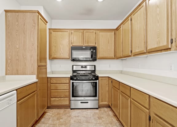a kitchen with white countertops and wooden cabinets