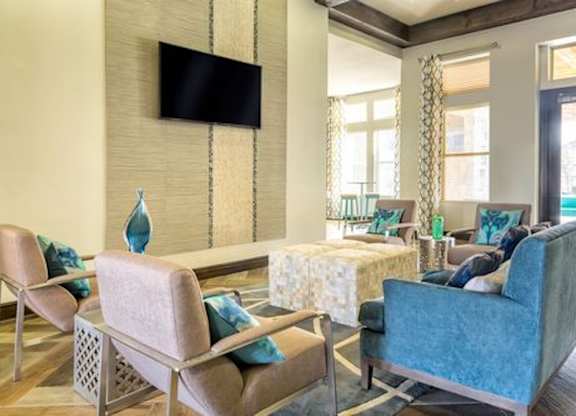 A living room with a blue couch and a television mounted on the wall.