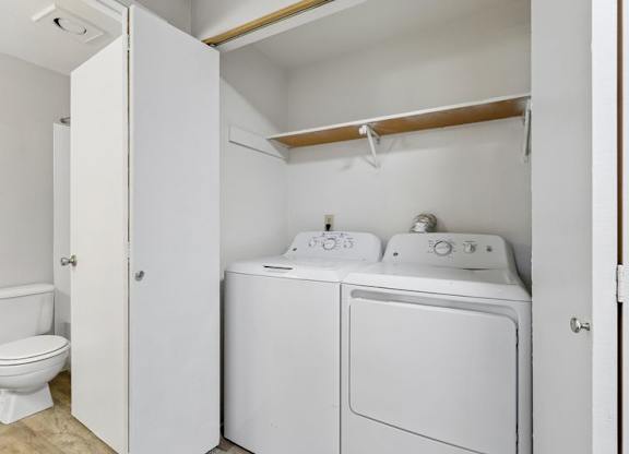 A white laundry room with a toilet and a washer and dryer.
