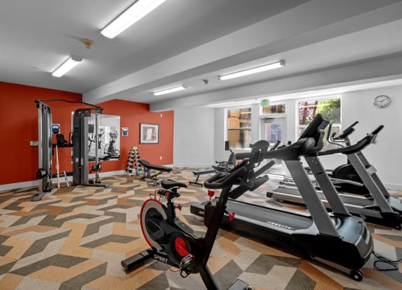 a gym with treadmills and other exercise equipment in a room with red walls