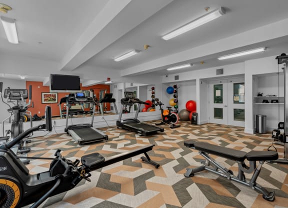 On-site fitness center with machines, weights, and tv at Collins Circle apartments in the Goose Hollow district in Portland, Oregon.