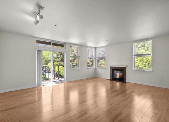 an empty living room with a wood floor and a fireplace