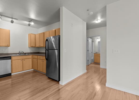 View of kitchen and hallway with wood-style flooring and white walls at Collins Circle apartments in the Goose Hollow district in Portland, Oregon.
